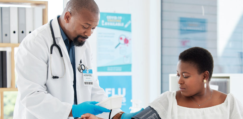 A male doctor checking up the blood pressure of a female