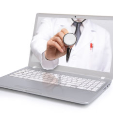 A doctor holding a stethoscope on a laptop